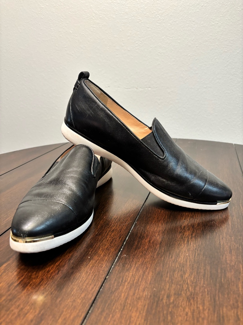 Cole Haan Black Leather Slip-On Sneakers with White Sole and Gold Toe Accent